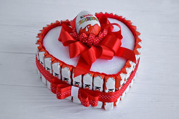 Коробка собрана как новогодние конфетные часы. На край коробки в форме сердца приклеить плоскую форму конфеты и положить конфету внутрь, внешнее украшение может содержать много конфет или нет